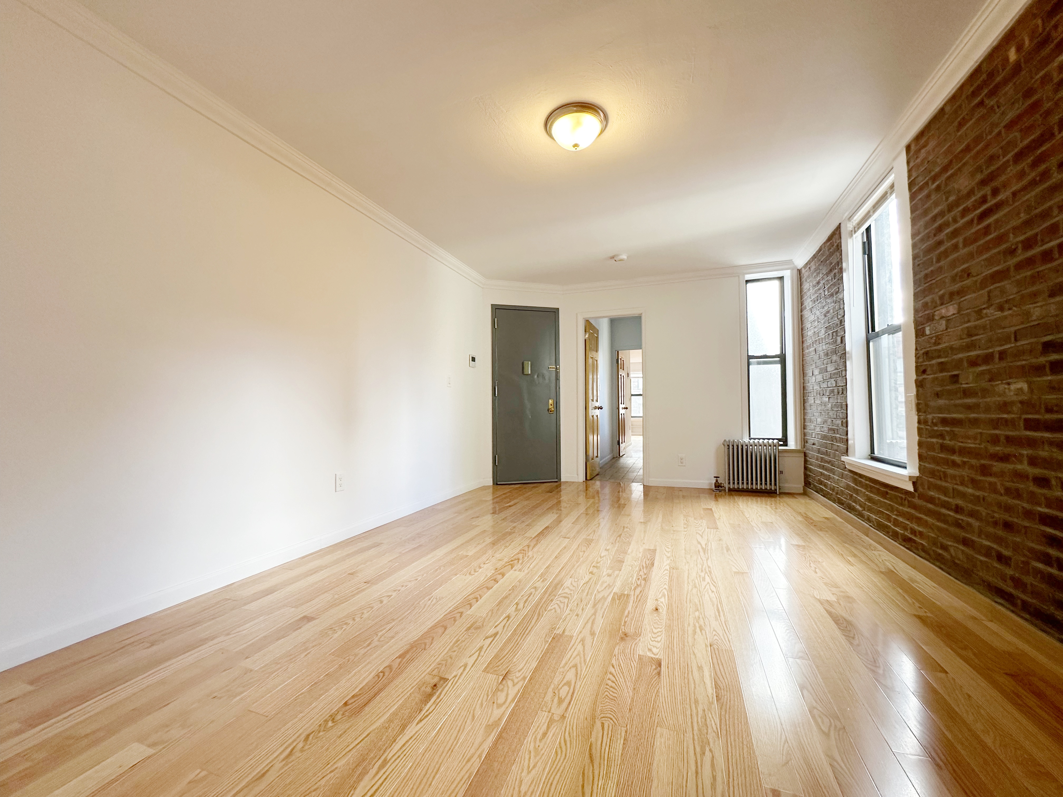 75 Madison Street, Unit 9 Manhattan, NY 10002 - Photo 2 of 6 a view of an empty room with wooden floor and a window