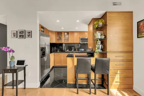 a kitchen with stainless steel appliances kitchen island granite countertop a refrigerator a stove and a dining table with wooden floor