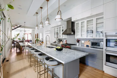 a kitchen with stainless steel appliances a table chairs in it and wooden floors