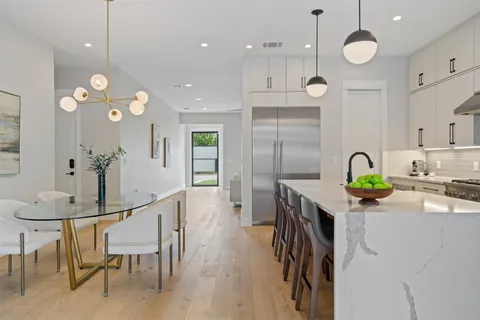 a kitchen with kitchen island stainless steel appliances a table chairs in it and wooden floors