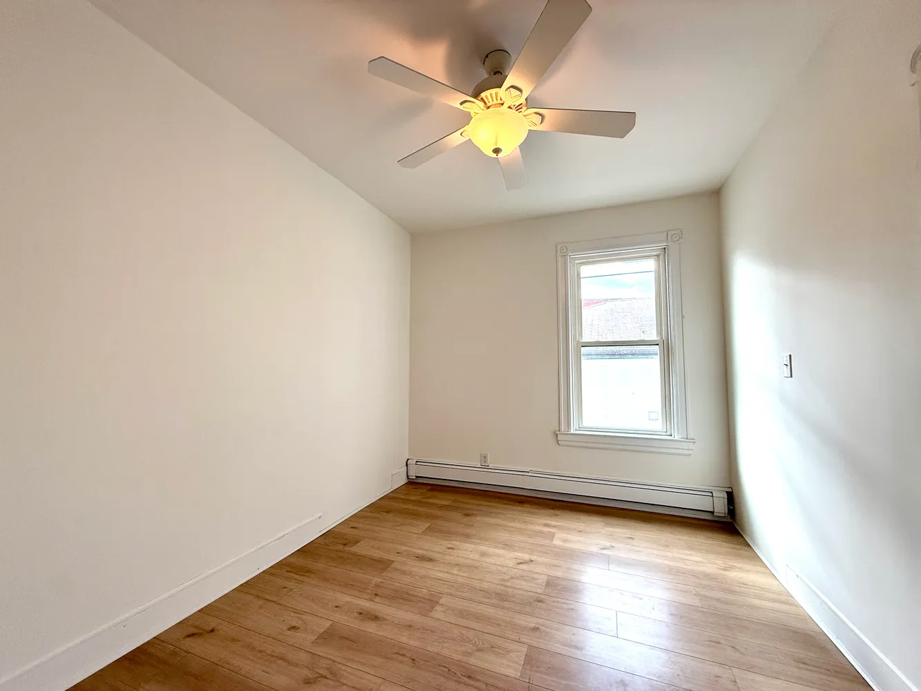 an empty room with wooden floor and window