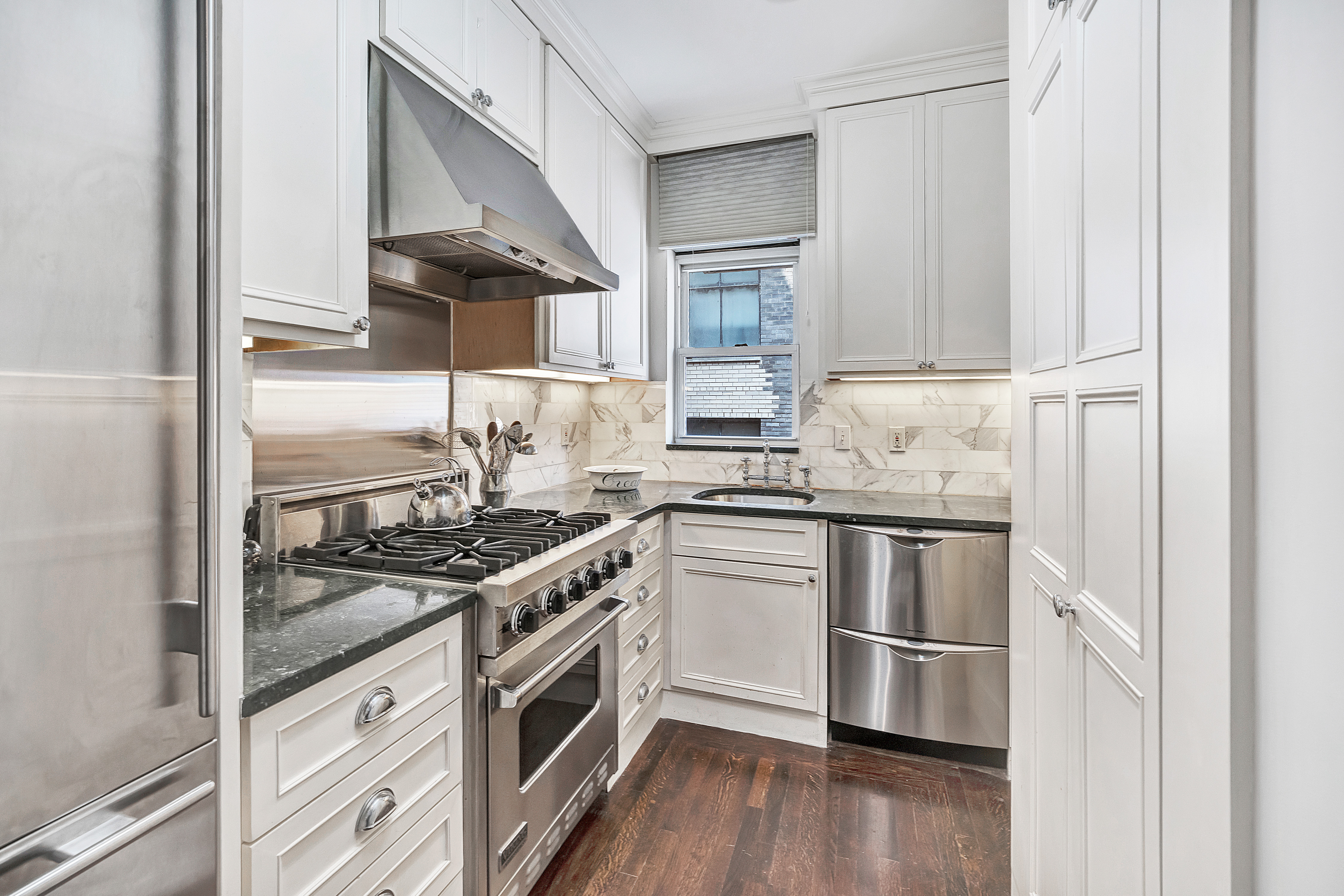 1060 Park Avenue, Unit 13G Manhattan, NY 10128 - Photo 5 of 11 a kitchen with stainless steel appliances granite countertop a stove a sink and a refrigerator