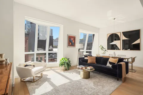 a living room with furniture potted plant and kitchen view