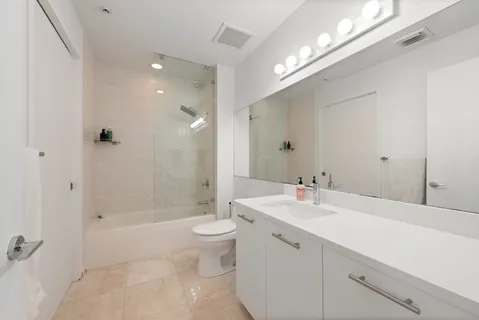 a bathroom with a bathtub shower sink mirror and toilet