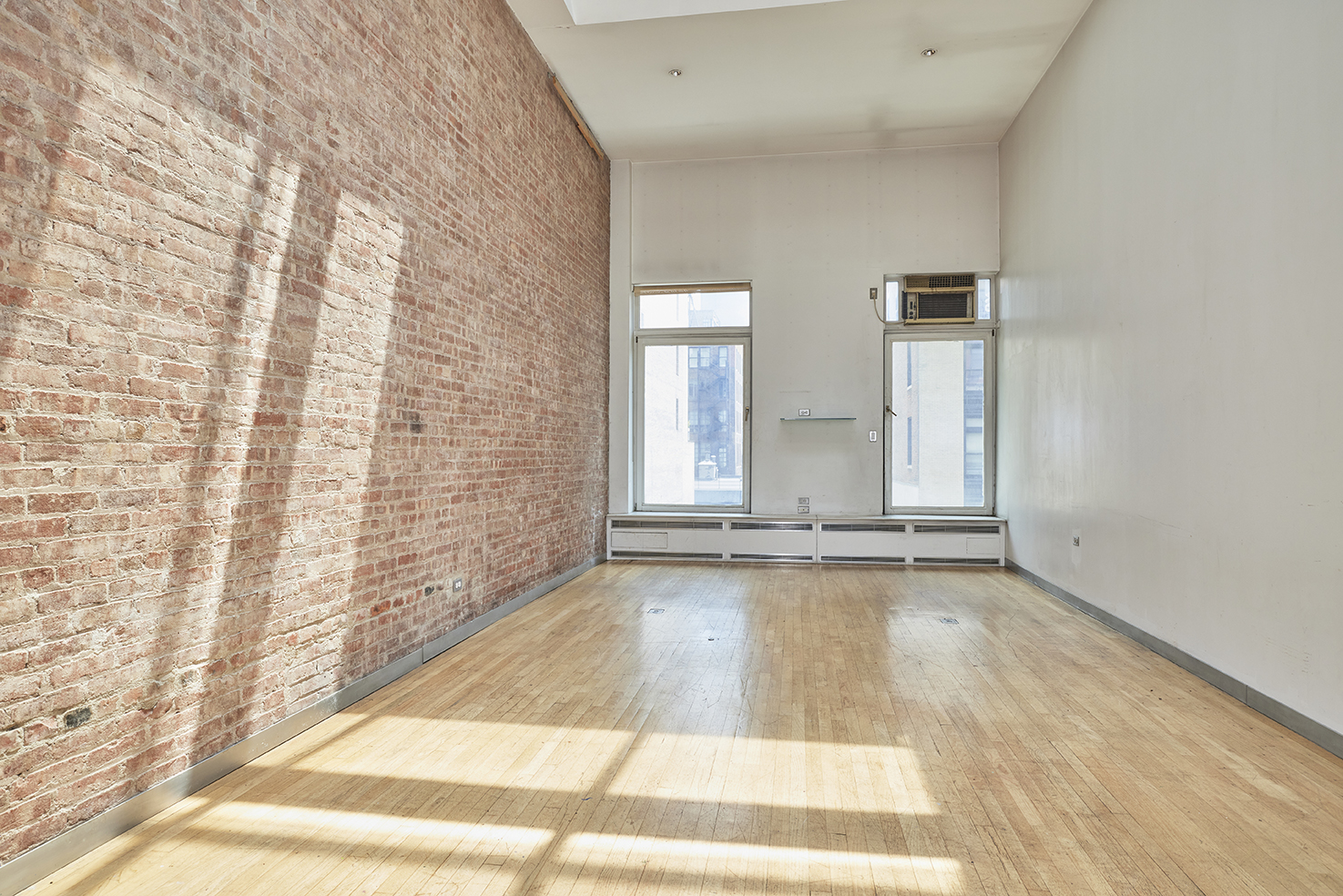 250 Mercer Street, Unit C603 Manhattan, NY 10012 - Photo 4 of 10 a view of an empty room with a fireplace and wooden floor