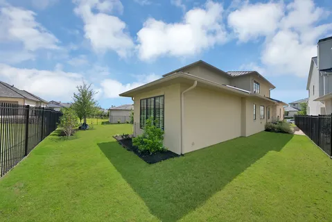 a yellow house sitting in the middle of a big yard with wooden fence