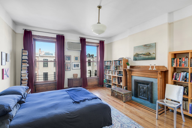 347 West 121st Street Manhattan, NY 10027 - Photo 9 of 16 a bedroom with a large bed a flat tv screen and a fireplace