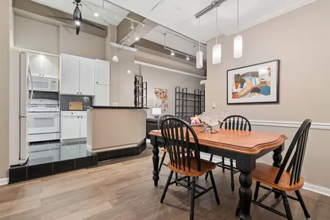 a dining room with wooden floor a chandelier a wooden table and chairs