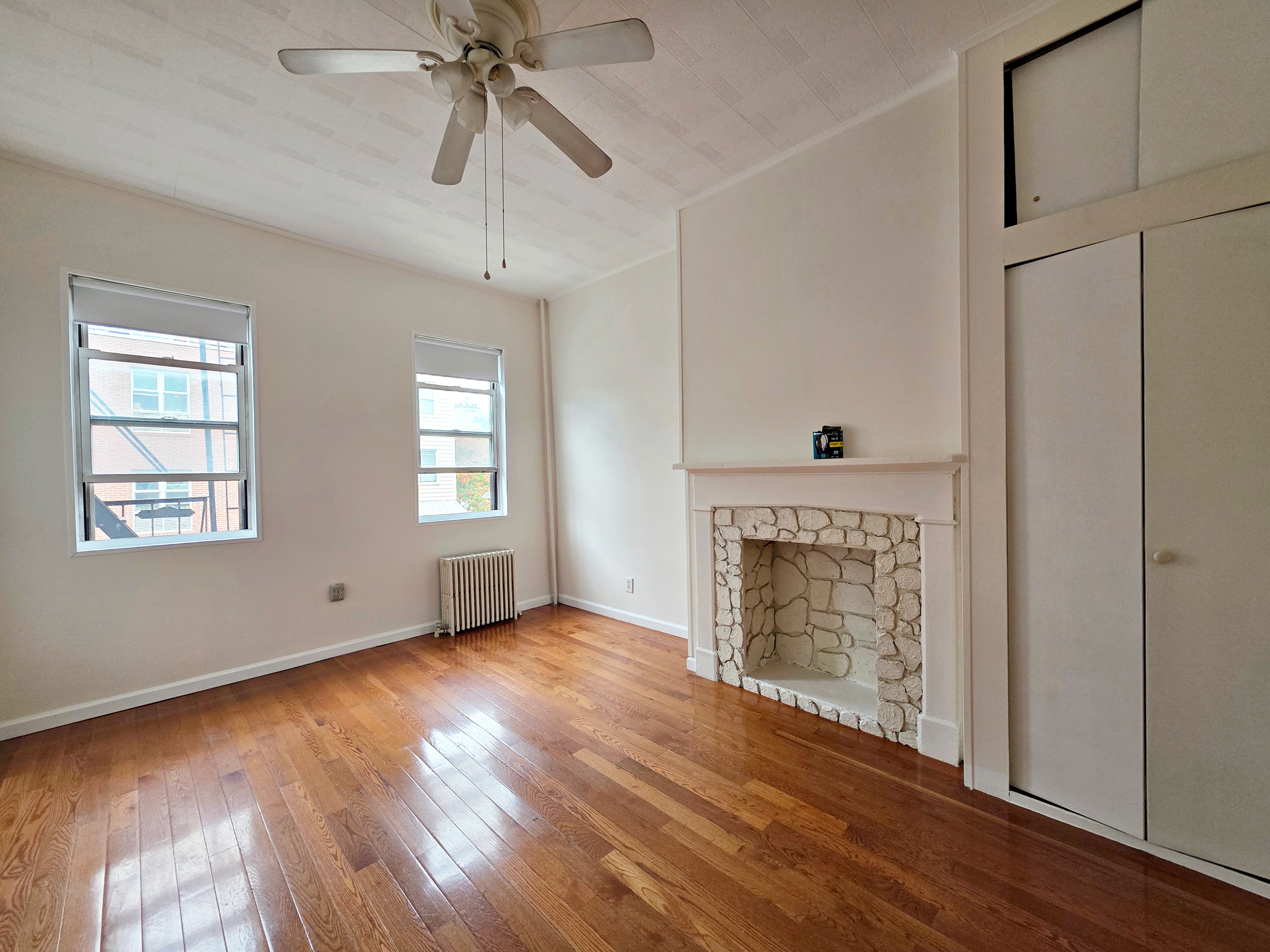 396 Manhattan Avenue, Unit 2L Brooklyn, NY 11211 - Photo 1 of 7 a view of an empty room with wooden floor fireplace and a window