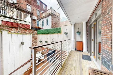 a view of a balcony with wooden floor and iron stairs
