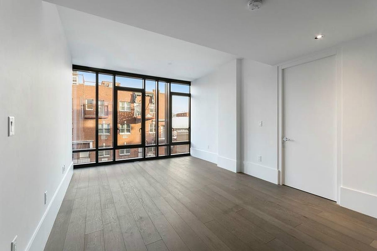 429 Kent Avenue, Unit 607 Brooklyn, NY 11249 - Photo 4 of 14 a view of an empty room with wooden floor and a window