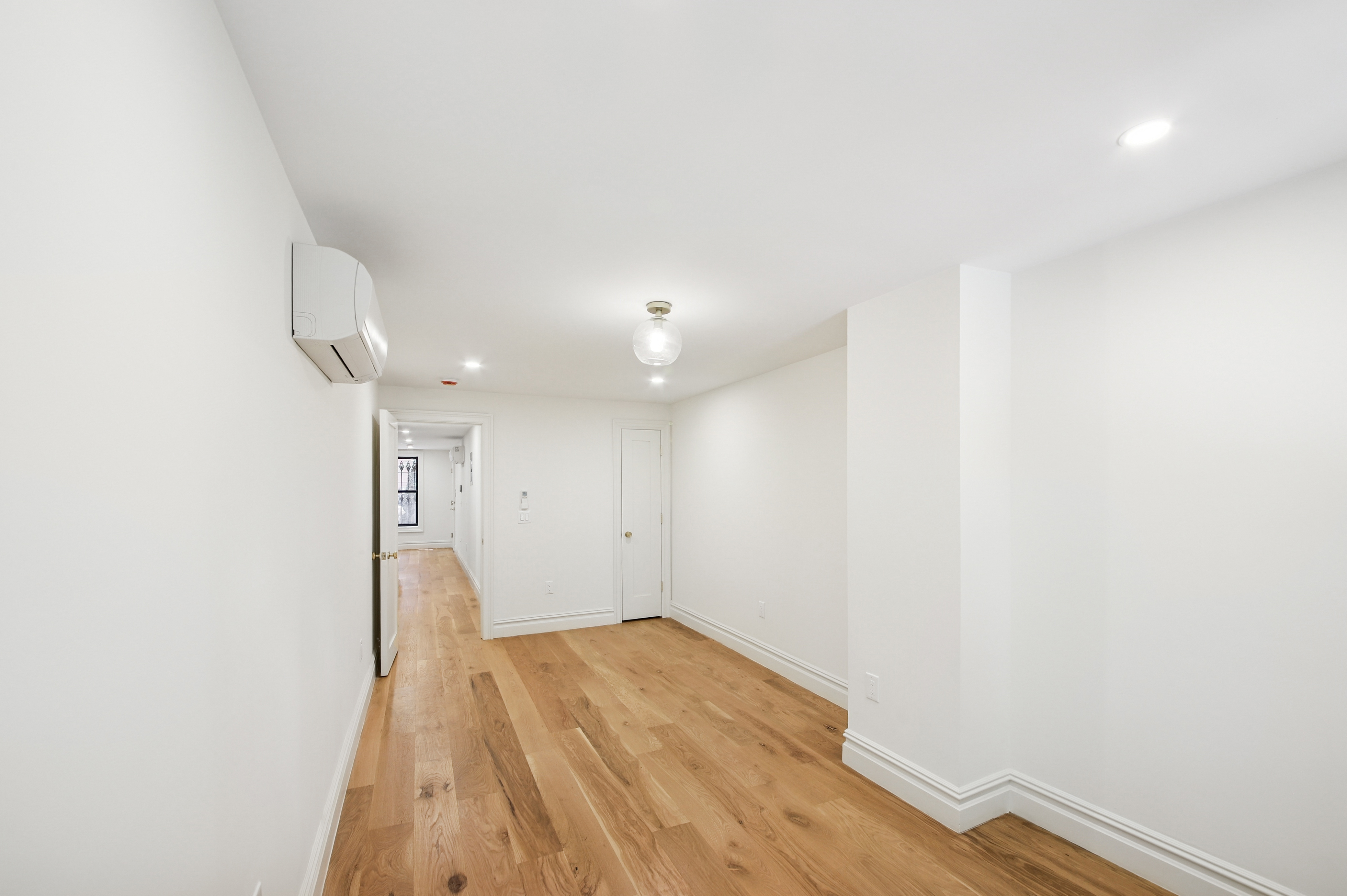 239 Madison Street, Unit 1 Brooklyn, NY 11216 - Photo 10 of 14 a view of empty room with wooden floor and fan