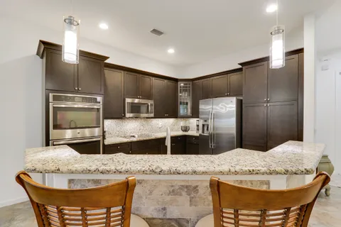 a kitchen with stainless steel appliances kitchen island granite countertop a sink and refrigerator
