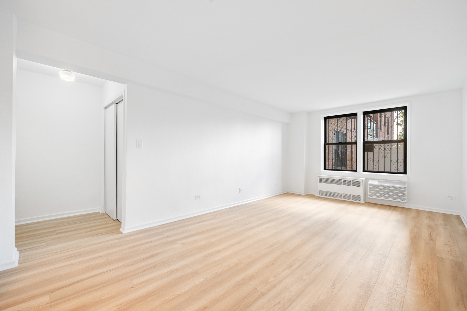 35-20 Leverich Street, Unit B226 Queens, NY 11372 - Photo 3 of 15 an empty room with wooden floor cabinet and windows