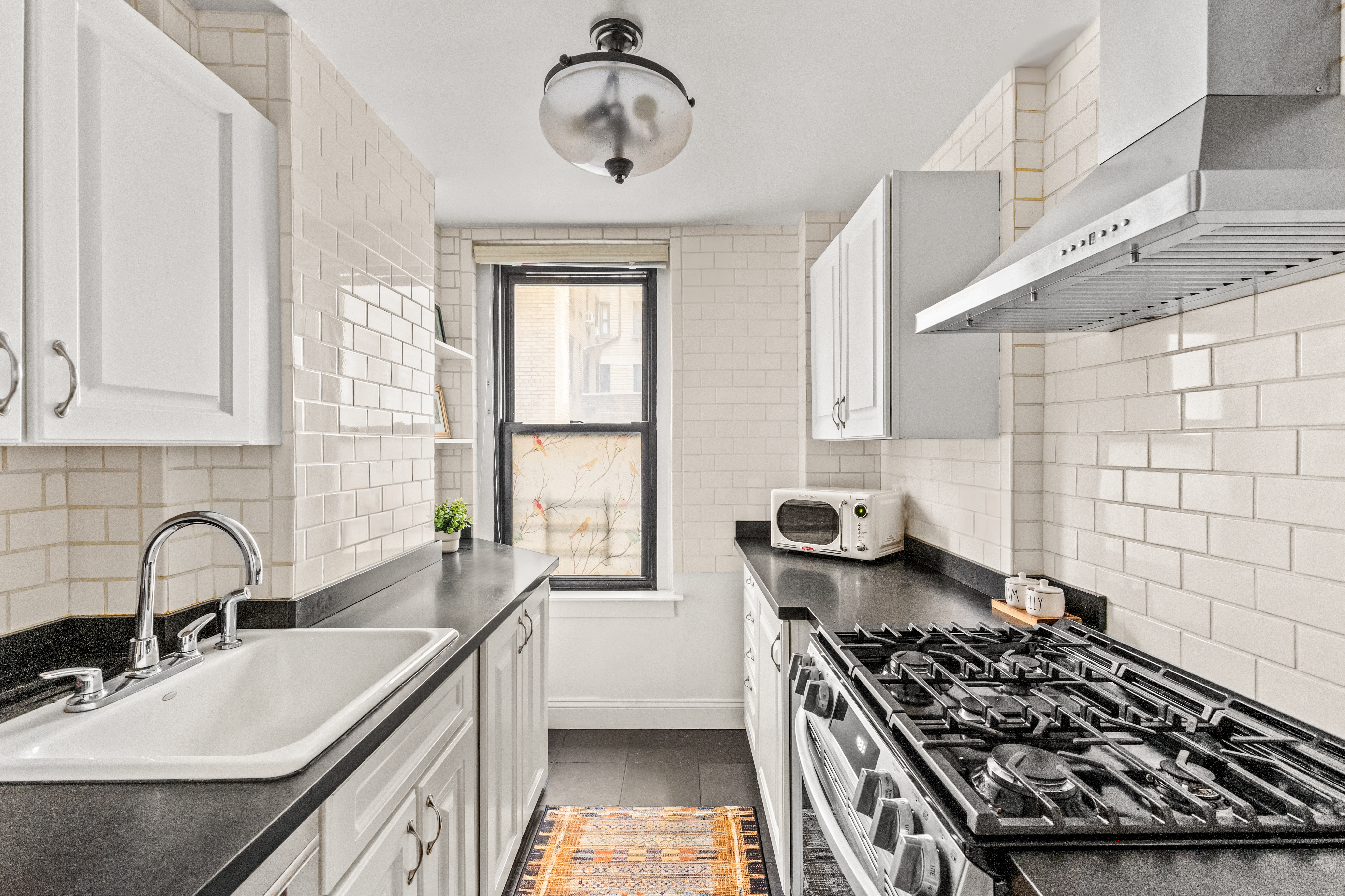 70 East 96th Street, Unit 2D Manhattan, NY 10128 - Photo 4 of 14 a kitchen with a stove a sink and a window