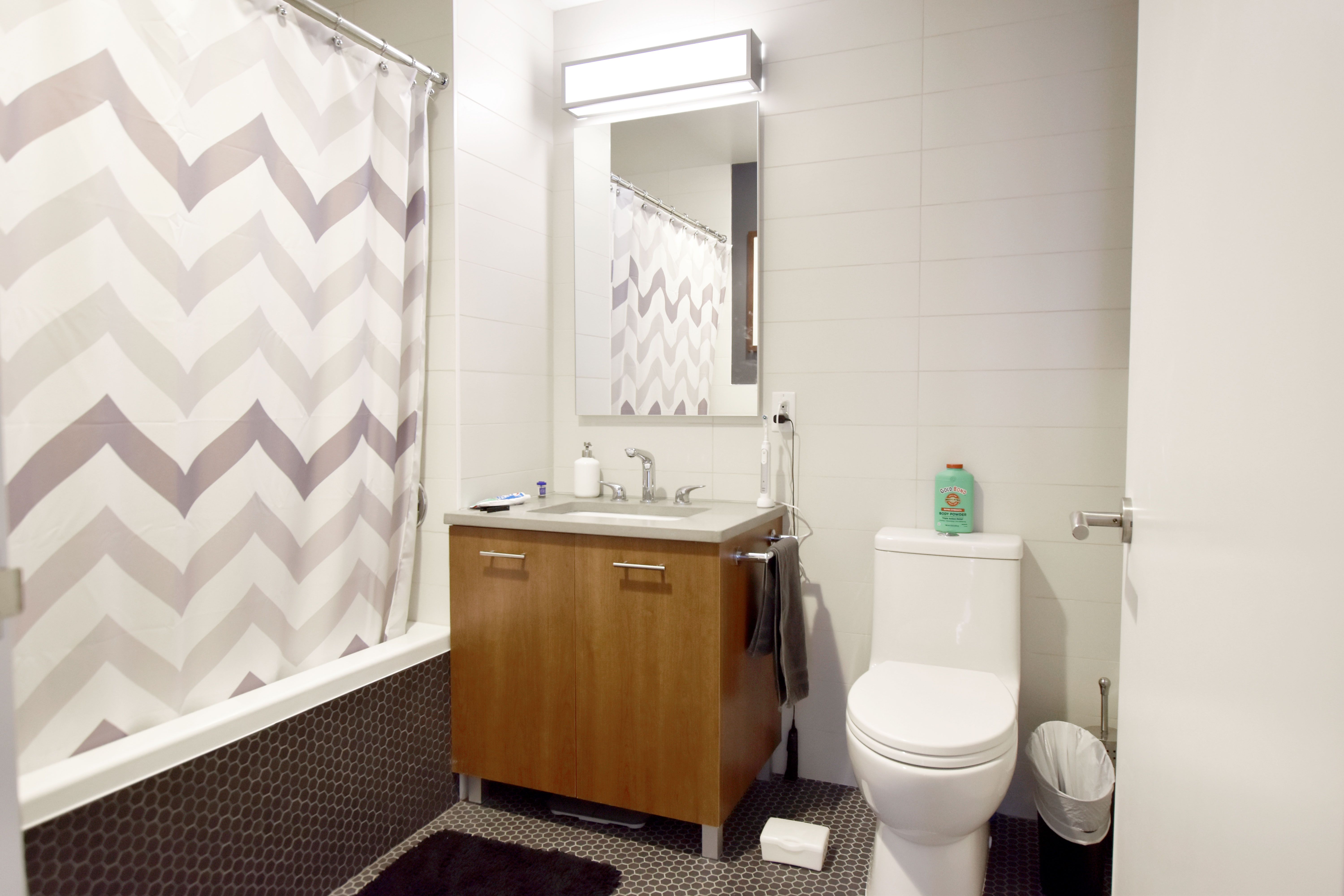 145 Clinton Street, Unit 4N Manhattan, NY 10002 - Photo 4 of 18 a bathroom with a granite countertop toilet sink and mirror