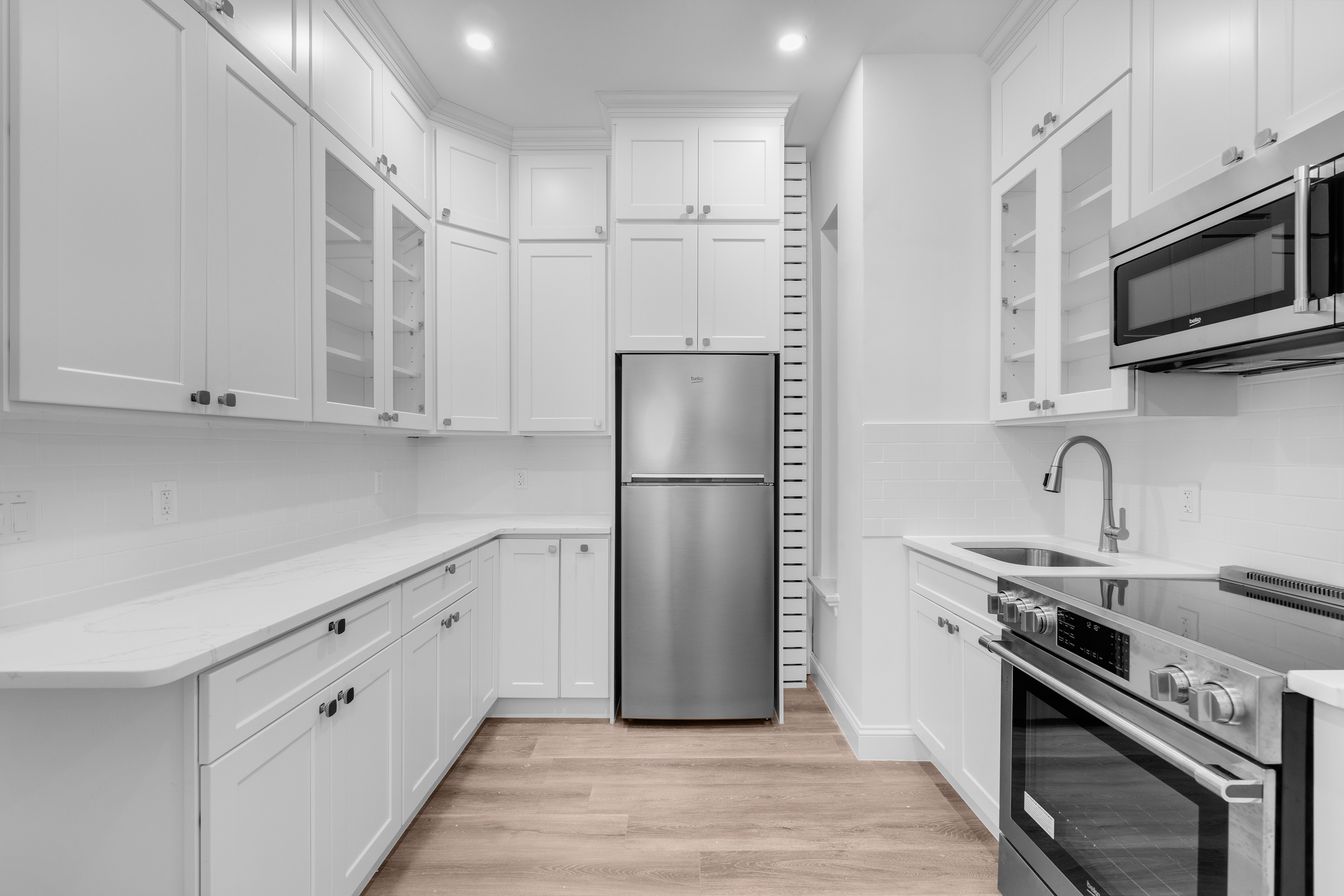 352 West 56th Street, Unit 2A Manhattan, NY 10019 - Photo 5 of 21 a kitchen with stainless steel appliances granite countertop a refrigerator sink and white cabinets
