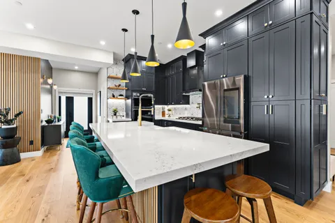 a kitchen with stainless steel appliances kitchen island granite countertop a refrigerator a stove a kitchen island a dining table and chairs with wooden floor