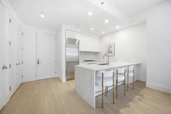 a kitchen with stainless steel appliances a table and chairs in it