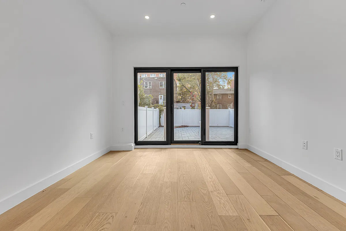 21-10 30th Avenue, Unit 1R Queens, NY 11102 - Photo 4 of 16 an empty room with wooden floor and windows