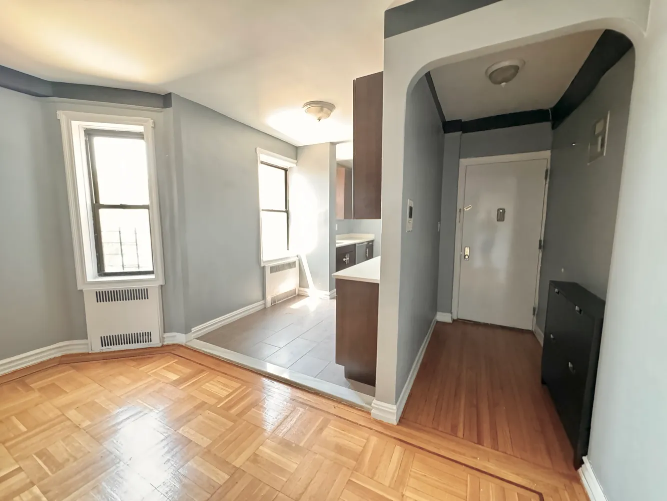 a view of an empty room with wooden floor and a window