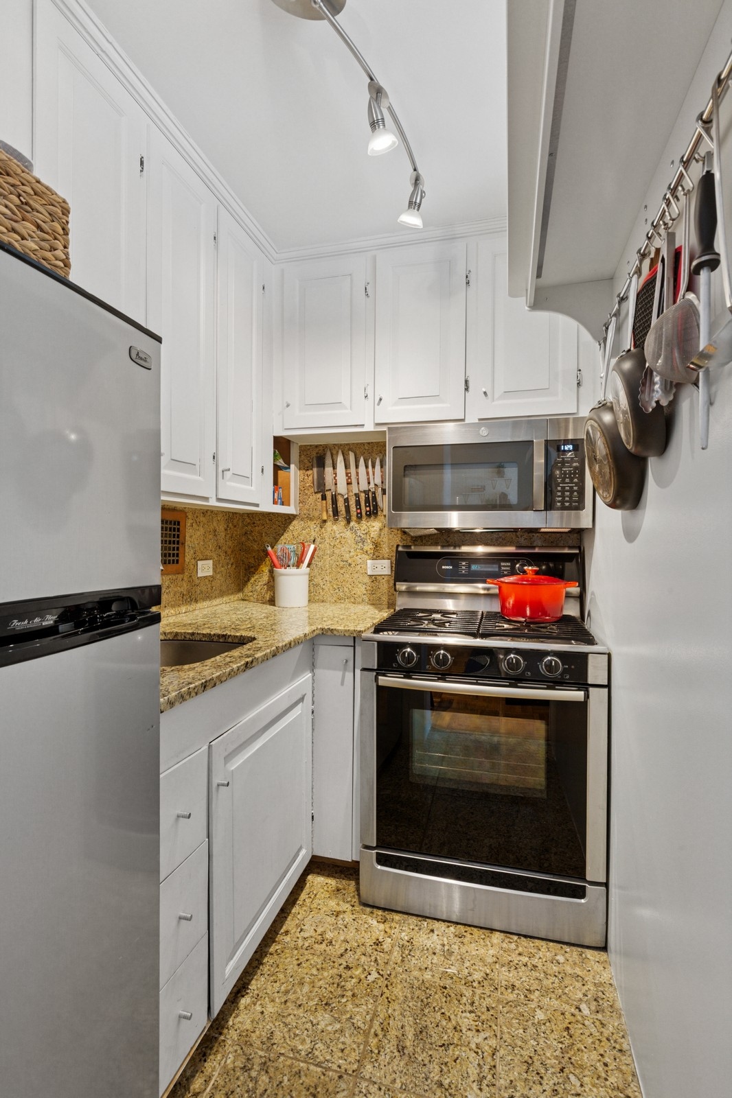 301 East 22nd Street, Unit 11U Manhattan, NY 10010 - Photo 3 of 11 a kitchen with stainless steel appliances granite countertop a stove and a refrigerator