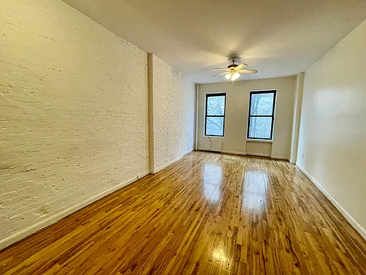 1105 1st Avenue, Unit 9 Manhattan, NY 10065 - Photo 1 of 8 a view of empty room with wooden floor and fan