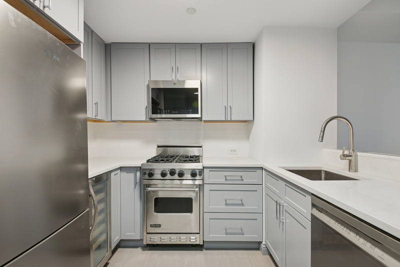 100 West 58th Street, Unit 5E Manhattan, NY 10019 - Photo 2 of 12 a kitchen with white cabinets stainless steel appliances and sink