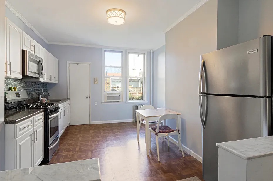 5-39 47th Road, Unit 2R Queens, NY 11101 - Photo 7 of 7 a kitchen with granite countertop a refrigerator a sink dishwasher a stove top oven a dining table and chairs with wooden floor
