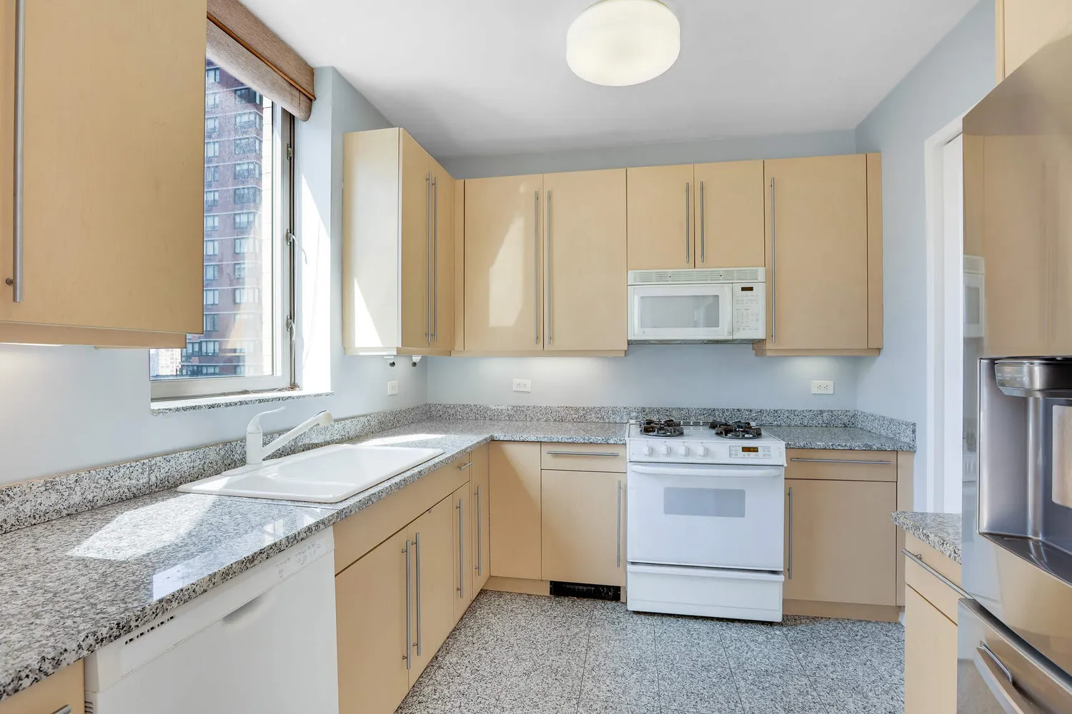 a kitchen with granite countertop white cabinets sink and window