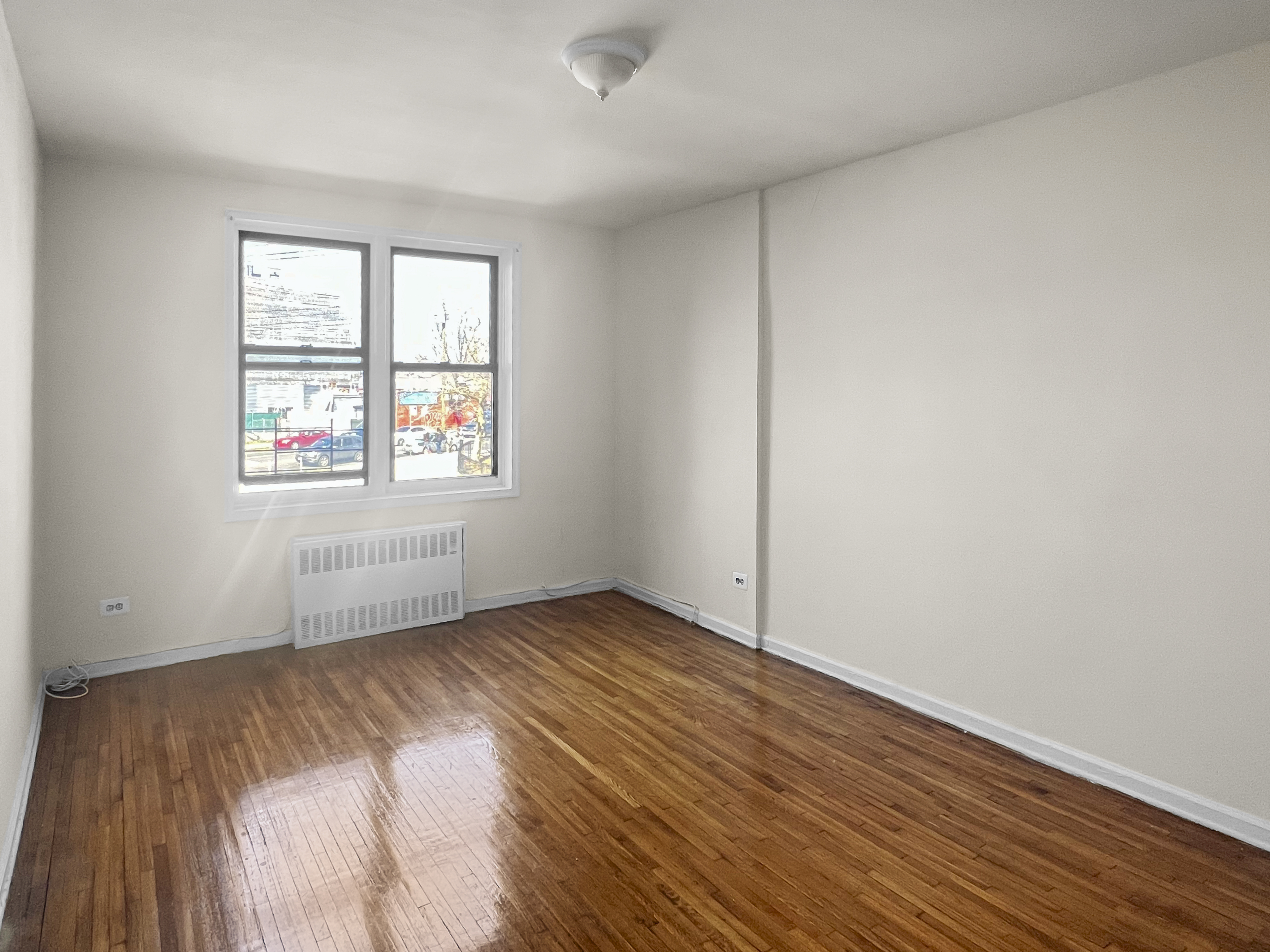 1466 East Gun Hill Road, Unit 1B Bronx, NY 10469 - Photo 3 of 5 an empty room with wooden floor and windows