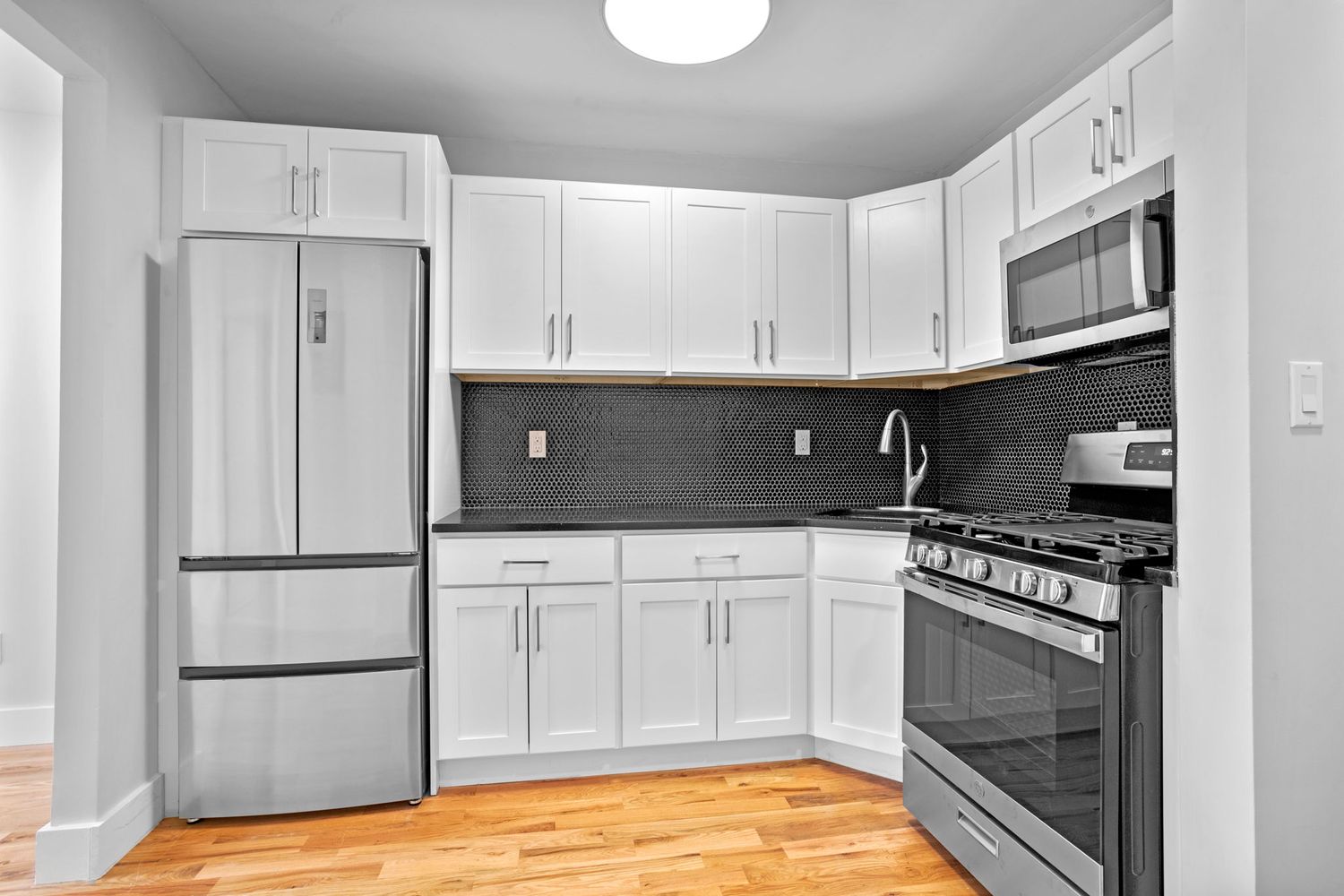 791 Lexington Avenue, Unit 2 Brooklyn, NY 11221 - Photo 5 of 19 a kitchen with granite countertop a refrigerator a stove a sink and white cabinets