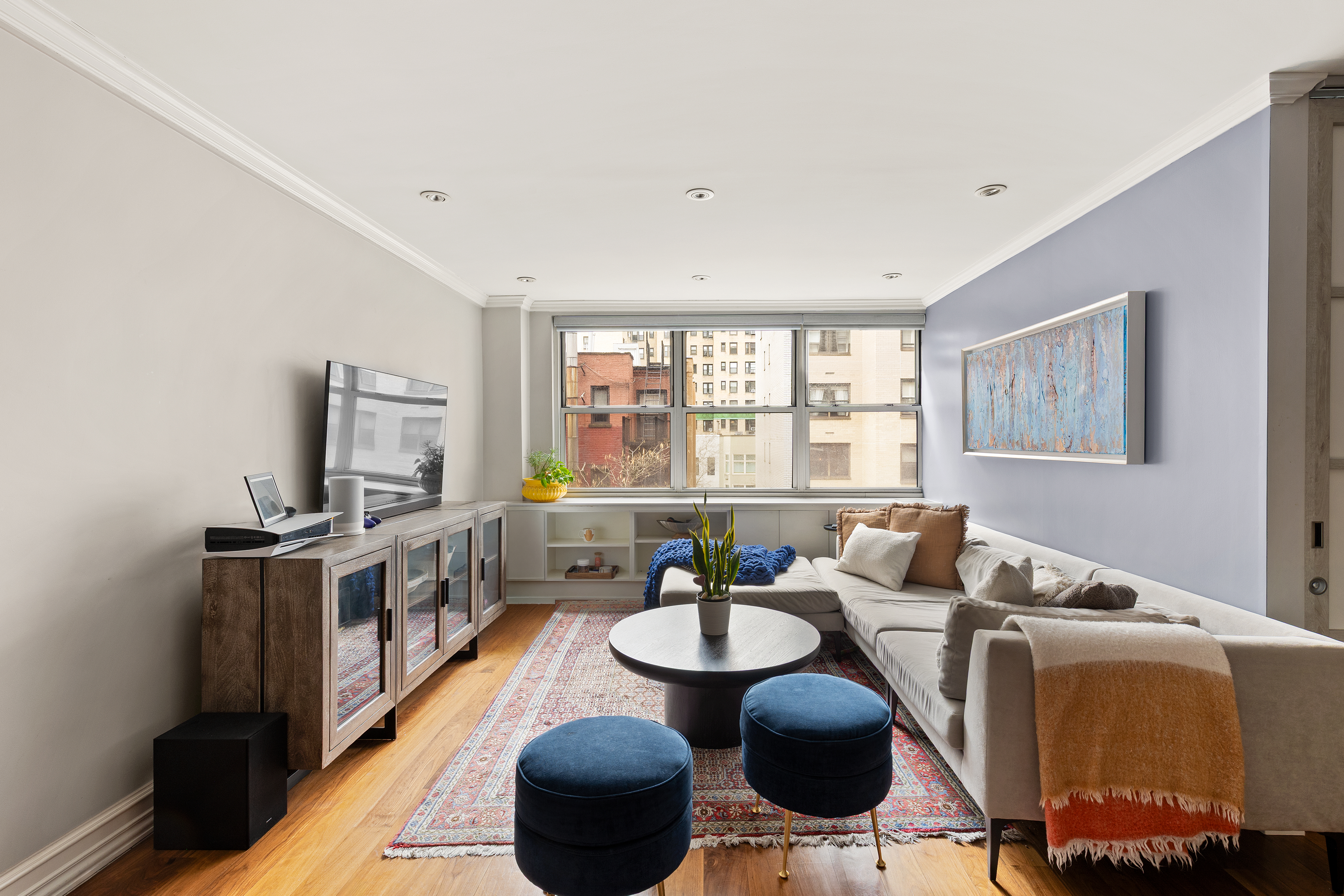 310 East 70th Street, Unit 6A Manhattan, NY 10021 - Photo 2 of 9 a living room with furniture a flat screen tv and a large window