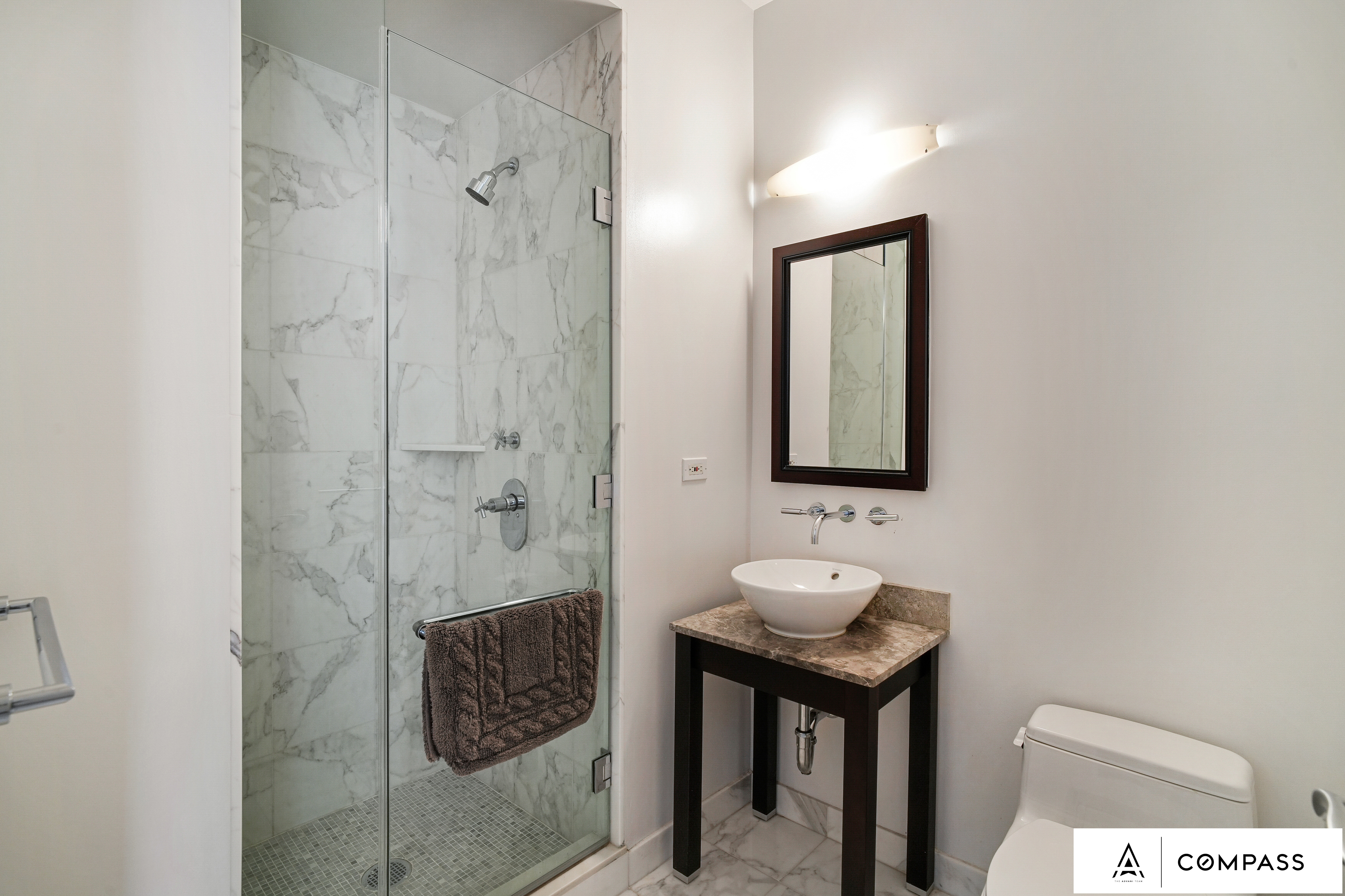 230 West 56th Street, Unit 49C Manhattan, NY 10019 - Photo 8 of 14 a bathroom with a toilet a sink and mirror