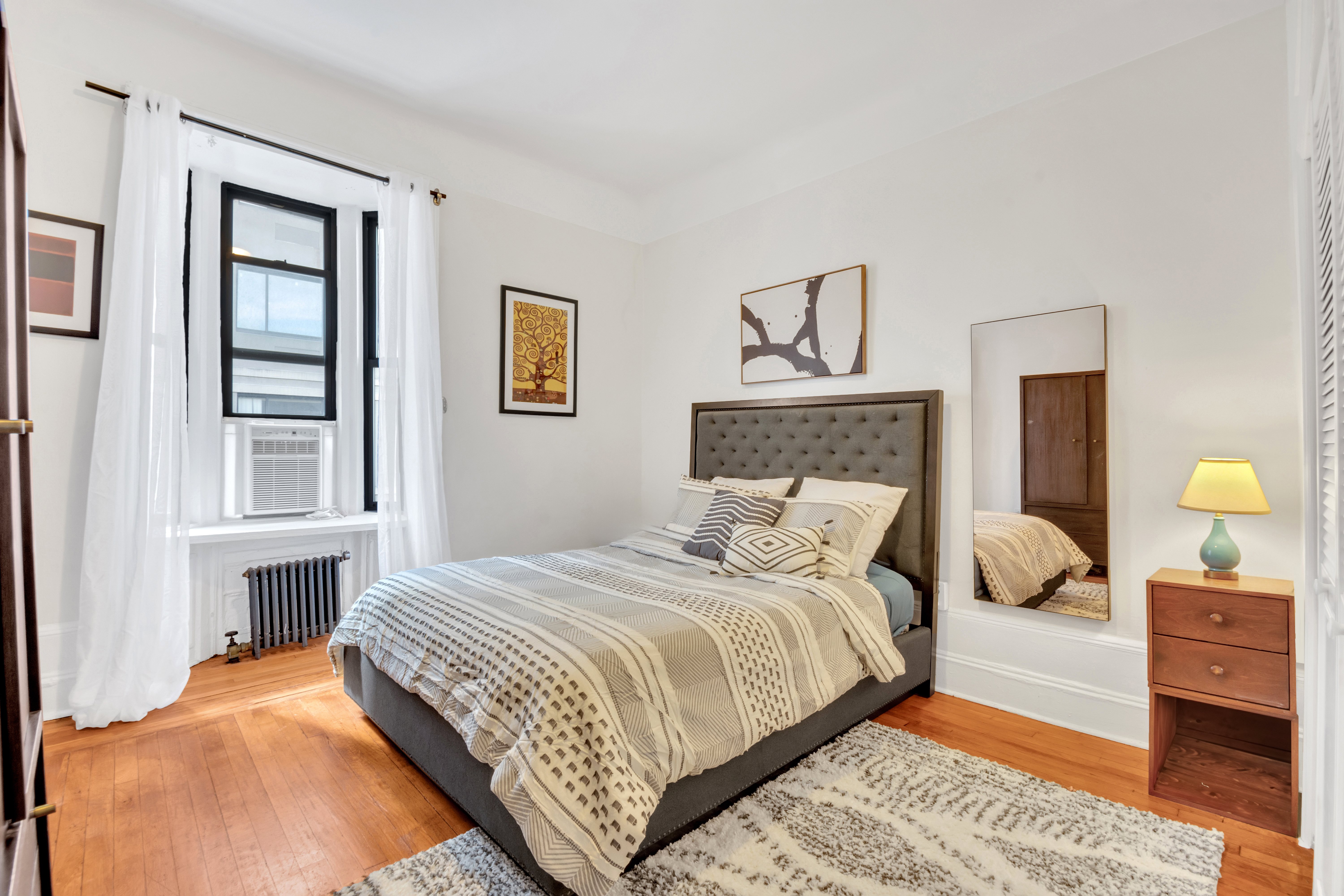 244 Riverside Drive, Unit 6K Manhattan, NY 10025 - Photo 6 of 8 a bedroom with a bed a lamp and dresser next to a window