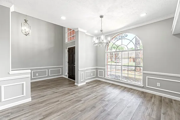 an empty room with wooden floor exposed radiator and windows