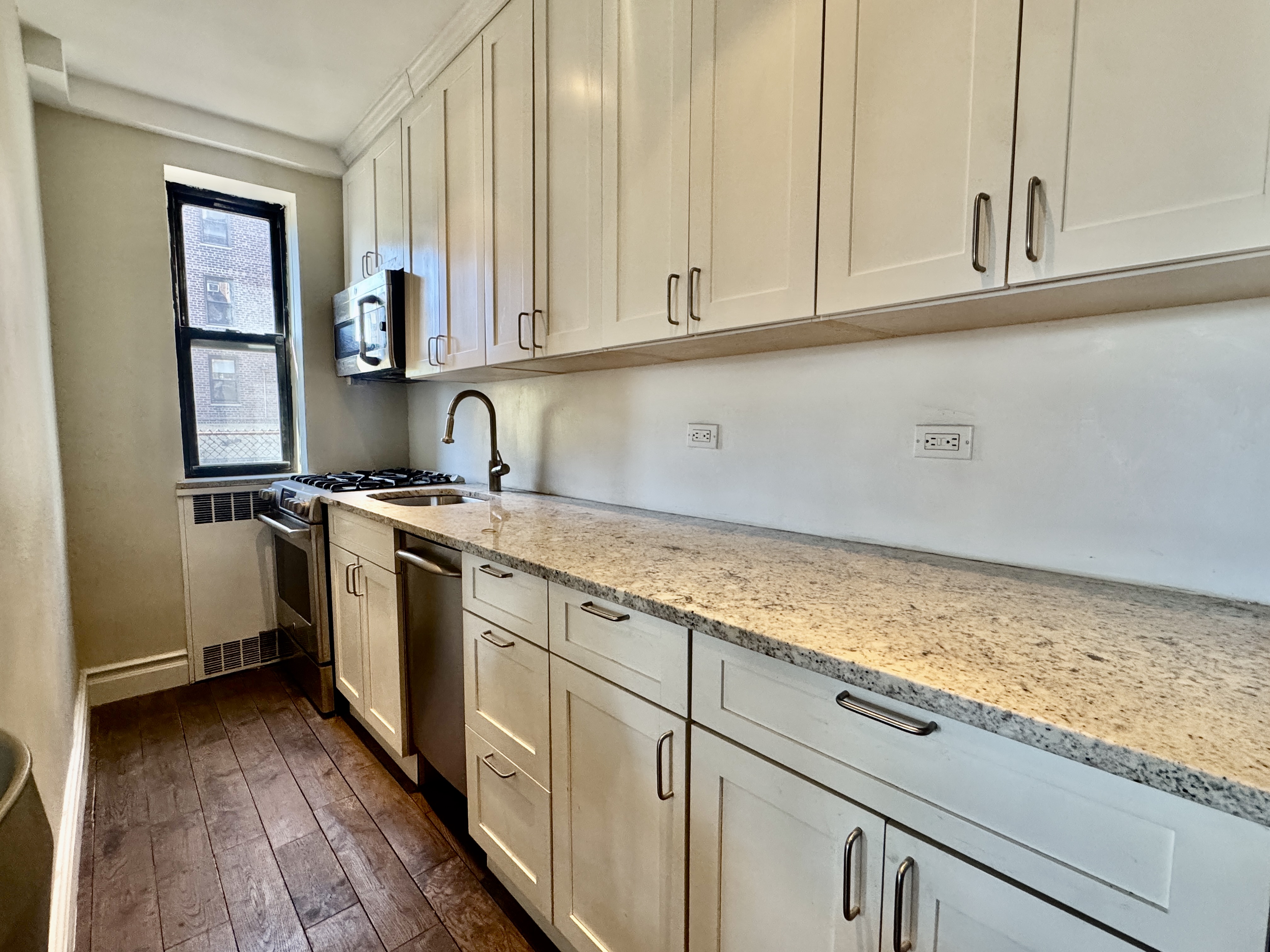 90 Park Terrace East, Unit 3B Manhattan, NY 10034 - Photo 6 of 13 a kitchen with granite countertop white cabinets and white appliances