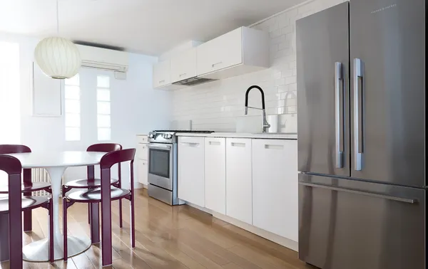 a kitchen with stainless steel appliances a refrigerator a table chairs and wooden floor