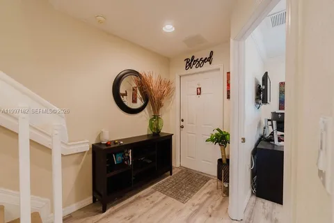 a view of a hallway with wooden floor and a potted plant