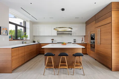 a kitchen with stainless steel appliances a sink a stove a refrigerator cabinets and a dining table