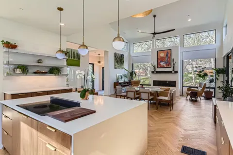 a kitchen with a stove a refrigerator and living room view