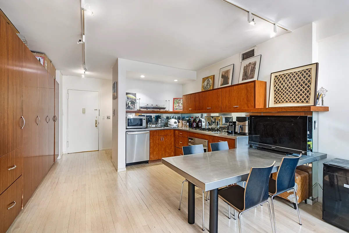 32 East 76th Street, Unit 502 Manhattan, NY 10021 - Photo 2 of 7 a kitchen with stainless steel appliances kitchen island granite countertop a refrigerator a stove a microwave oven with white cabinets and wooden floor
