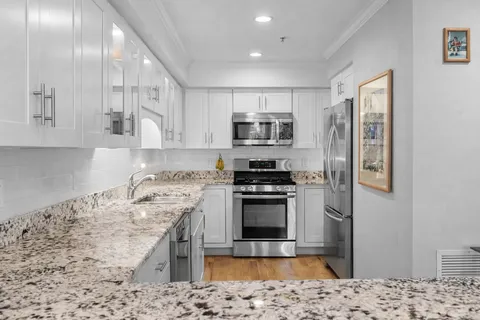 a kitchen with stainless steel appliances kitchen island granite countertop a sink stove and microwave