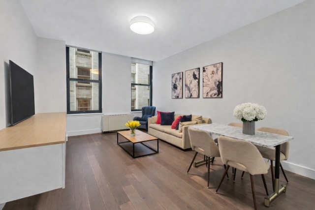 25 Broad Street, Unit 11K Manhattan, NY 10004 - Photo 3 of 16 a living room with furniture and a flat screen tv