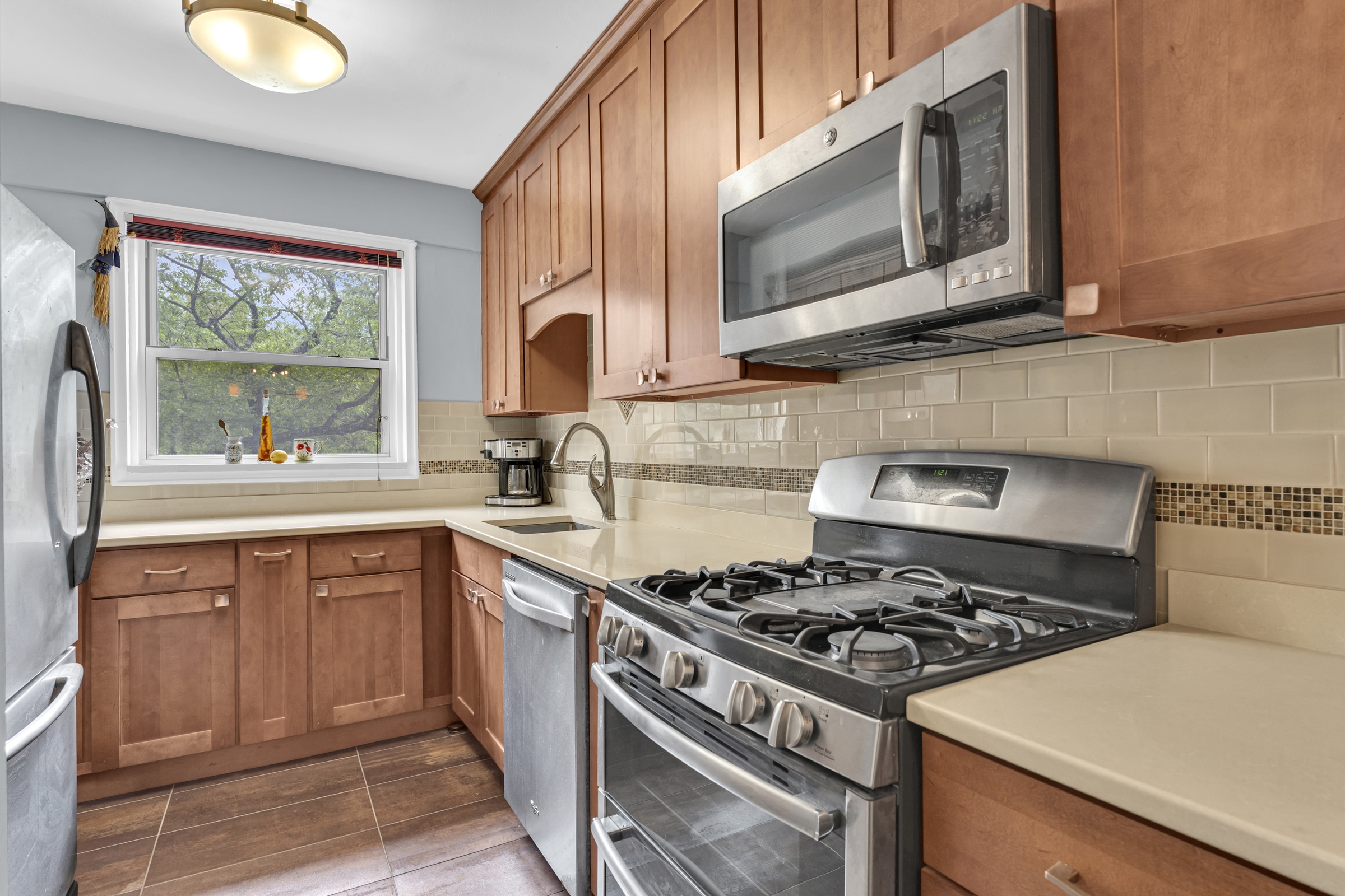 750 Kappock Street, Unit 307 Bronx, NY 10463 - Photo 4 of 20 a kitchen with stainless steel appliances granite countertop a stove top oven a sink dishwasher and cabinets with wooden floor