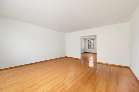 an empty room with wooden floor and natural light