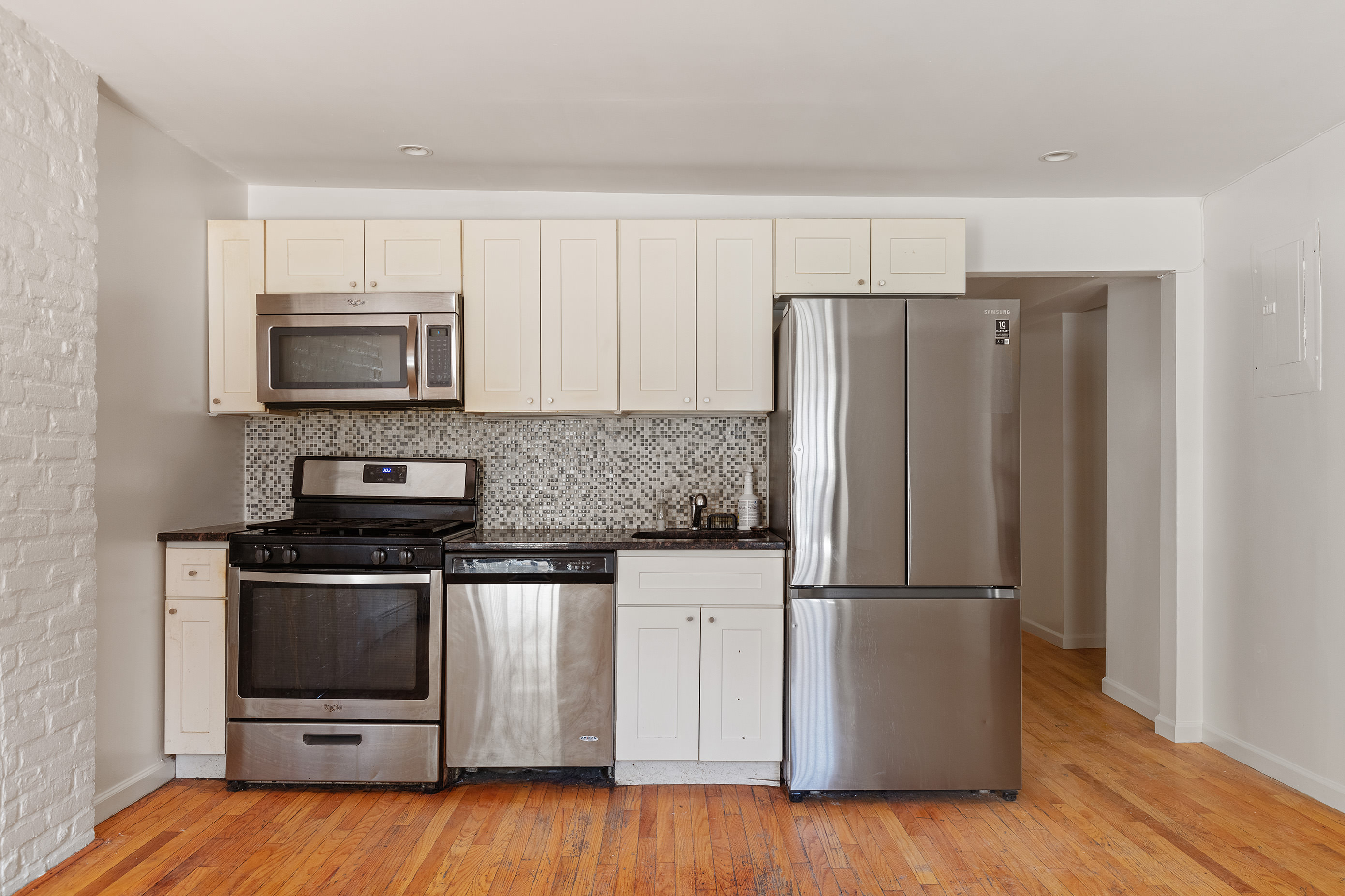 14 Covert Street, Unit 1 Brooklyn, NY 11207 - Photo 2 of 9 a kitchen with wooden cabinets and stainless steel appliances
