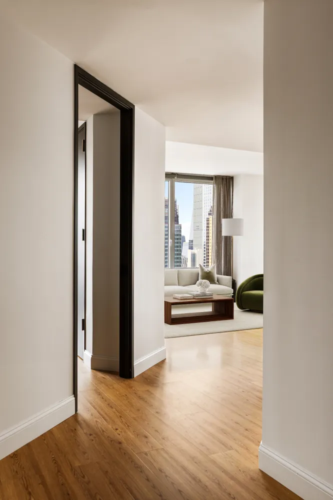 a view of a hallway with wooden floor and a living room