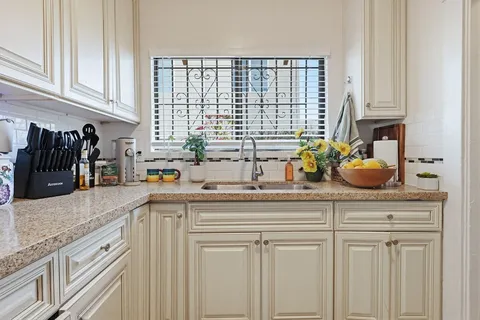 a kitchen with white cabinets and sink