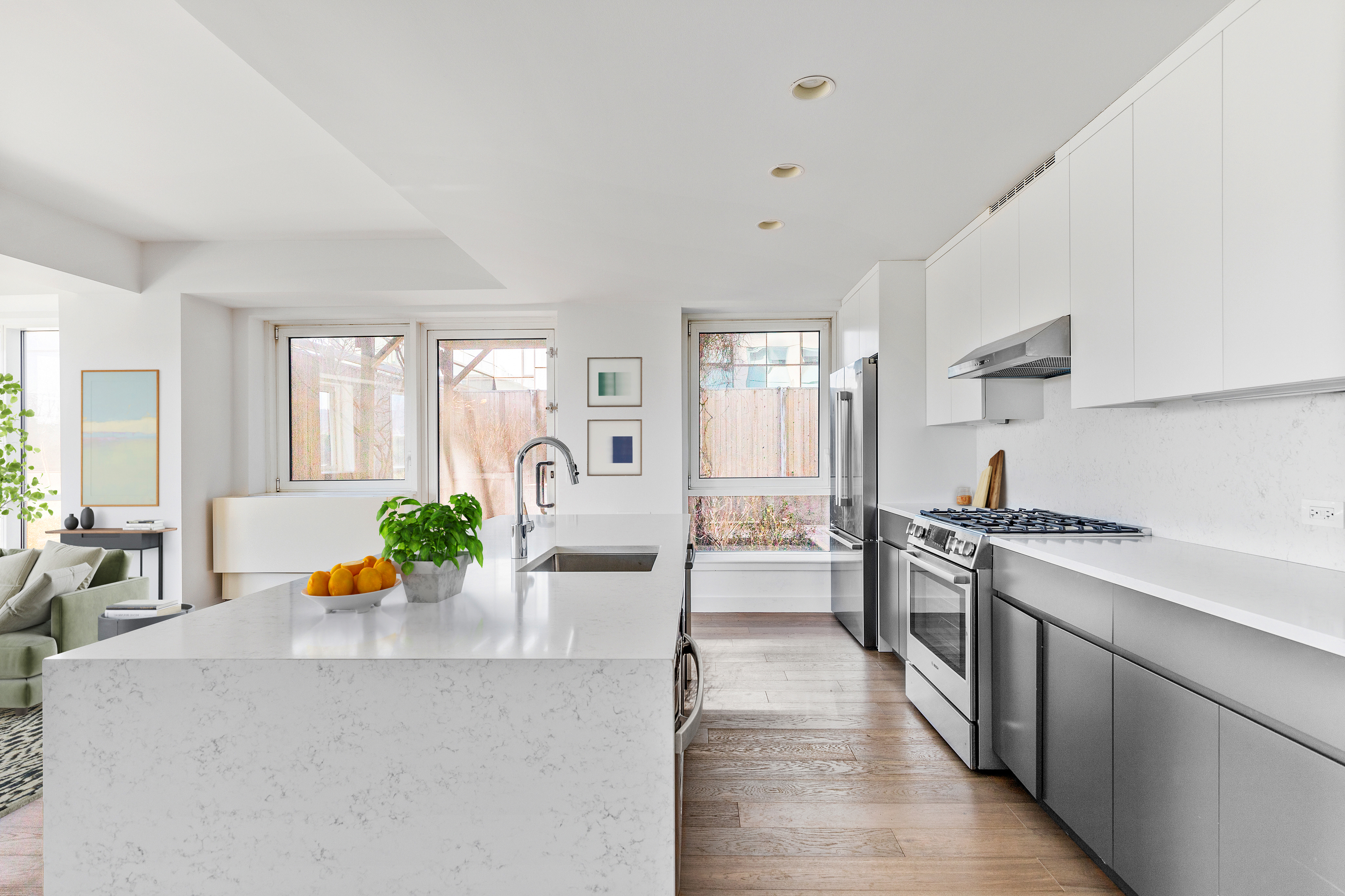 440 Kent Avenue, Unit 1B Brooklyn, NY 11249 - Photo 3 of 20 a large white kitchen with stainless steel appliances granite countertop a stove a sink a dining table and chairs